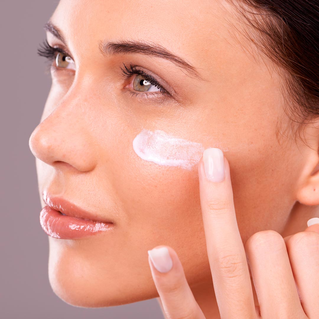 Femme mettant de la crème sur son visage pour des soins dermatologiques